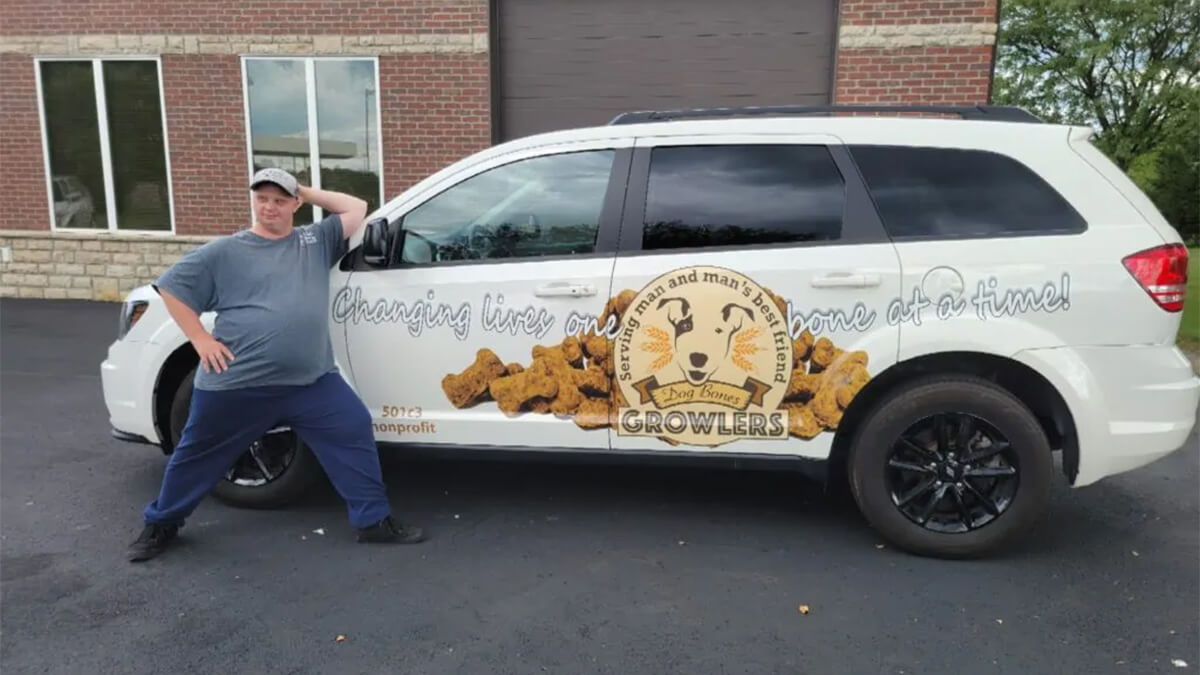 Atlas Butler HVAC Tech posing in front of a Growlers Dog Bones vehicle.