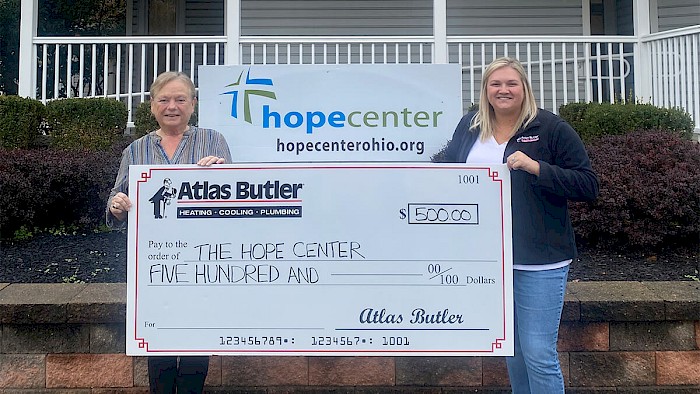 Women holding a check from Atlas Butler's Community Comfort & Care Program collaborating with the Hope Center to provide community service and empowerment in the Old East area of Columbus.